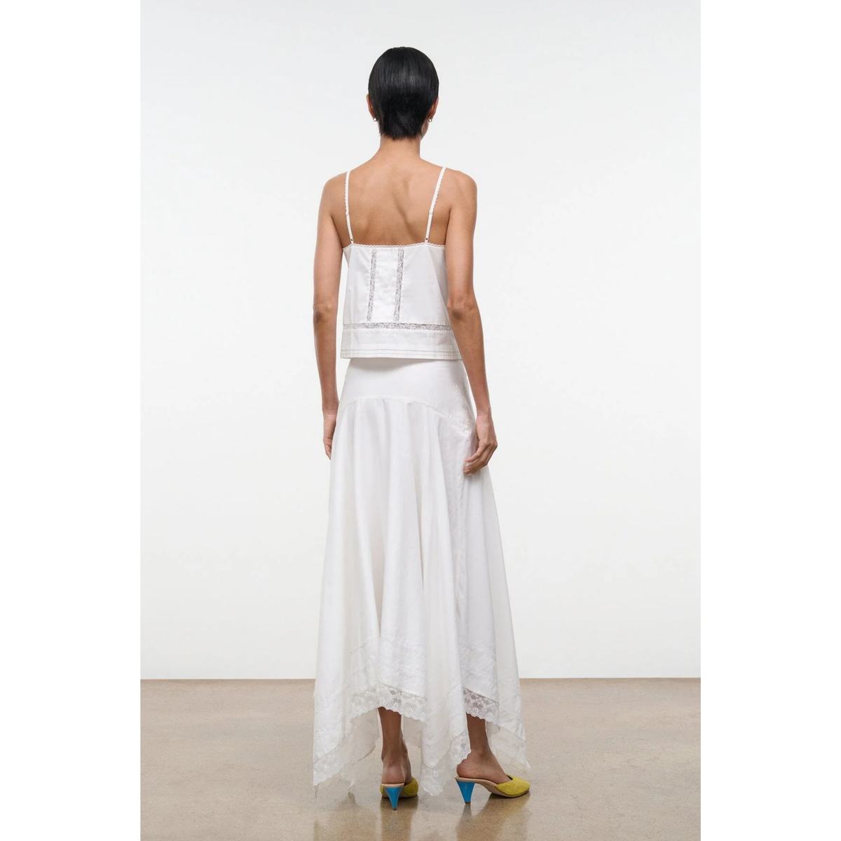 Woman wearing a white dress with thin straps on a plain background