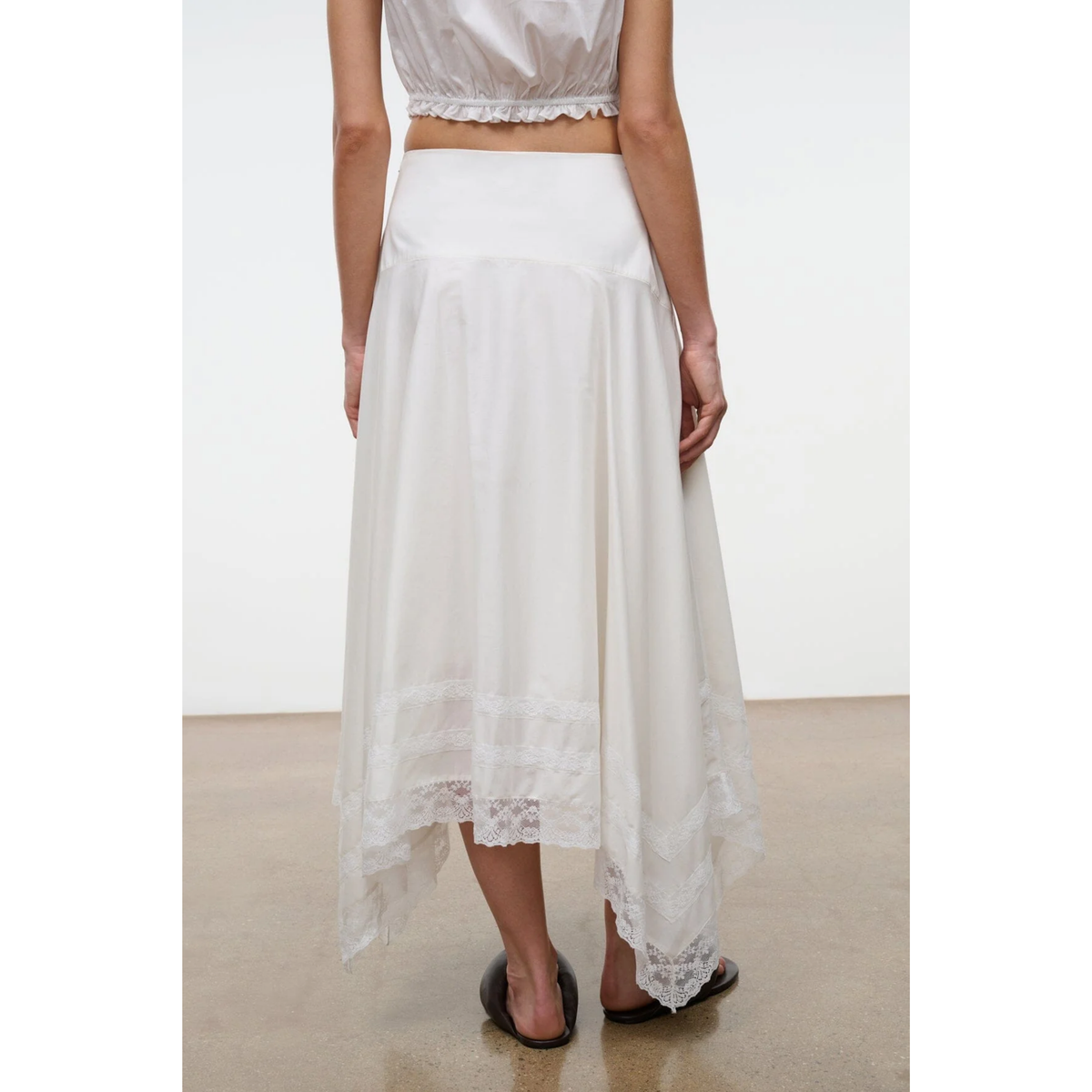 White lace skirt worn by a person on a plain background