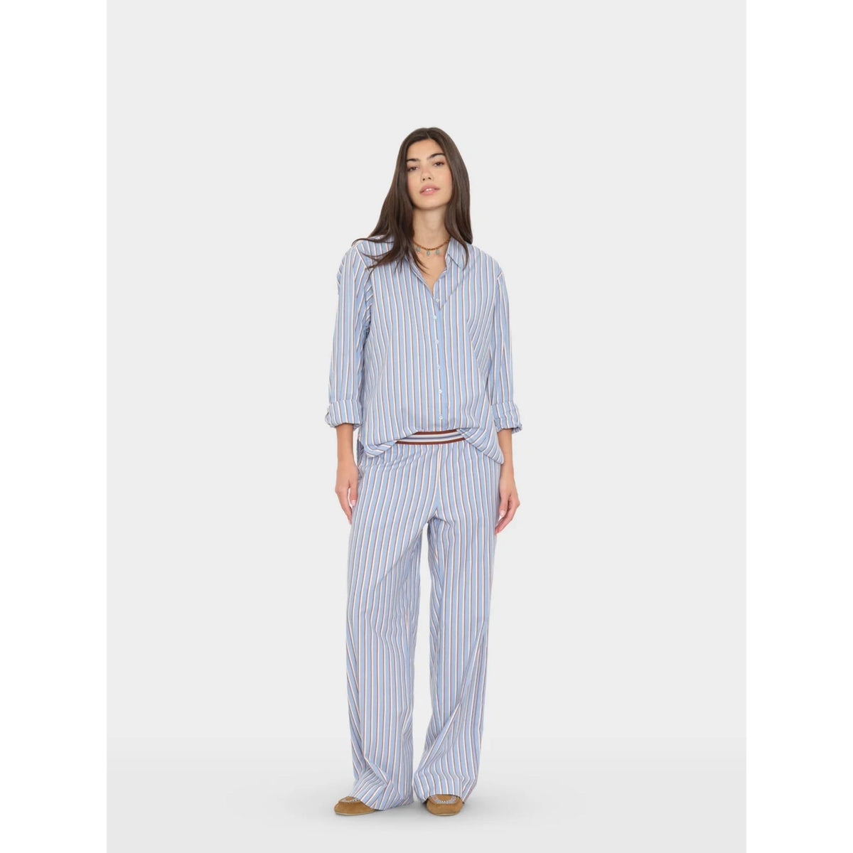 Full-length front view of a model wearing the light blue striped Alto Pant paired with a matching long-sleeve button-up shirt.