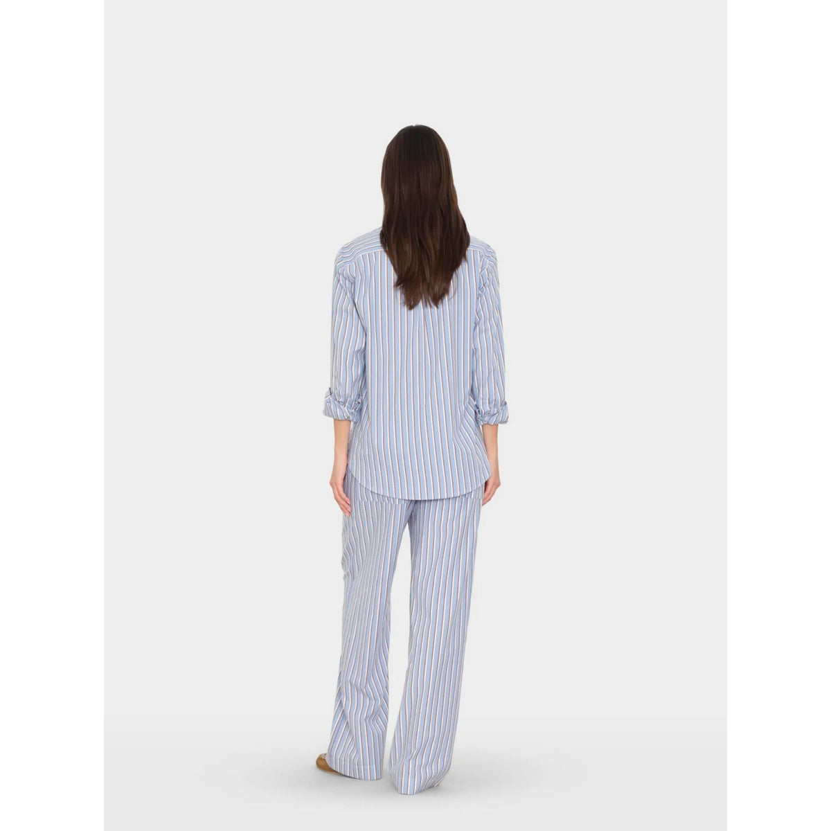 Full-length back view of a model wearing the light blue striped Alto Pant paired with a matching long-sleeve button-up shirt.