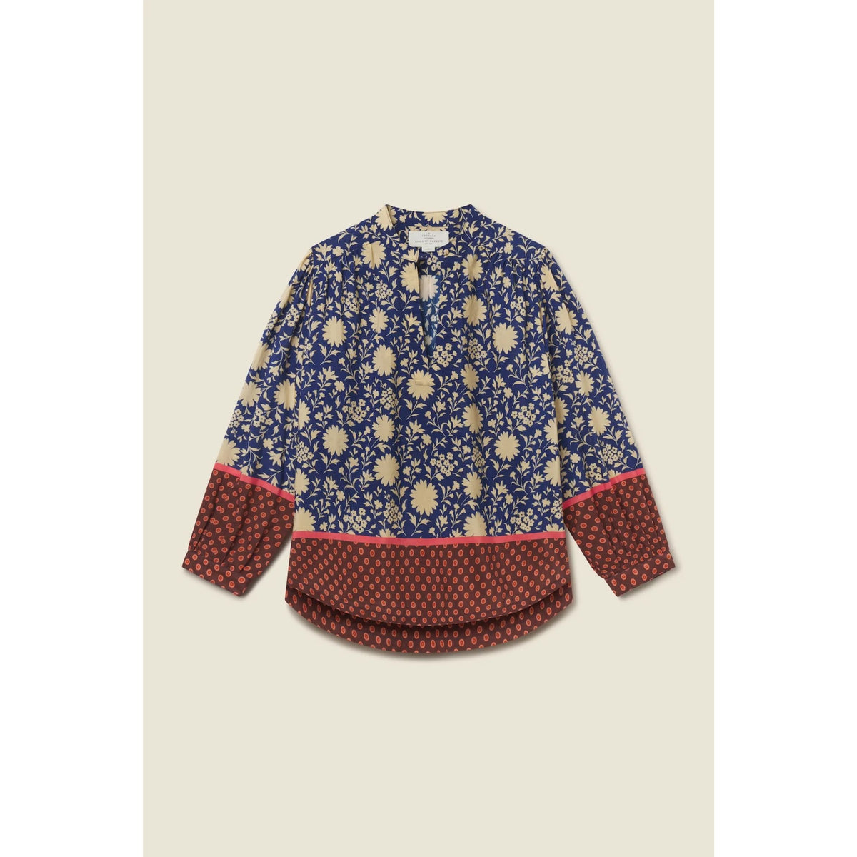 A long-sleeve blouse with a navy blue and beige floral print, featuring a solid rust-red patterned hem and cuffs with a thin pink accent line, laid flat on a light beige background.