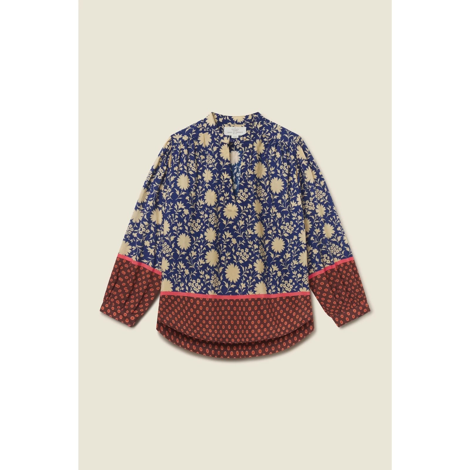 A long-sleeve blouse with a navy blue and beige floral print, featuring a solid rust-red patterned hem and cuffs with a thin pink accent line, laid flat on a light beige background.