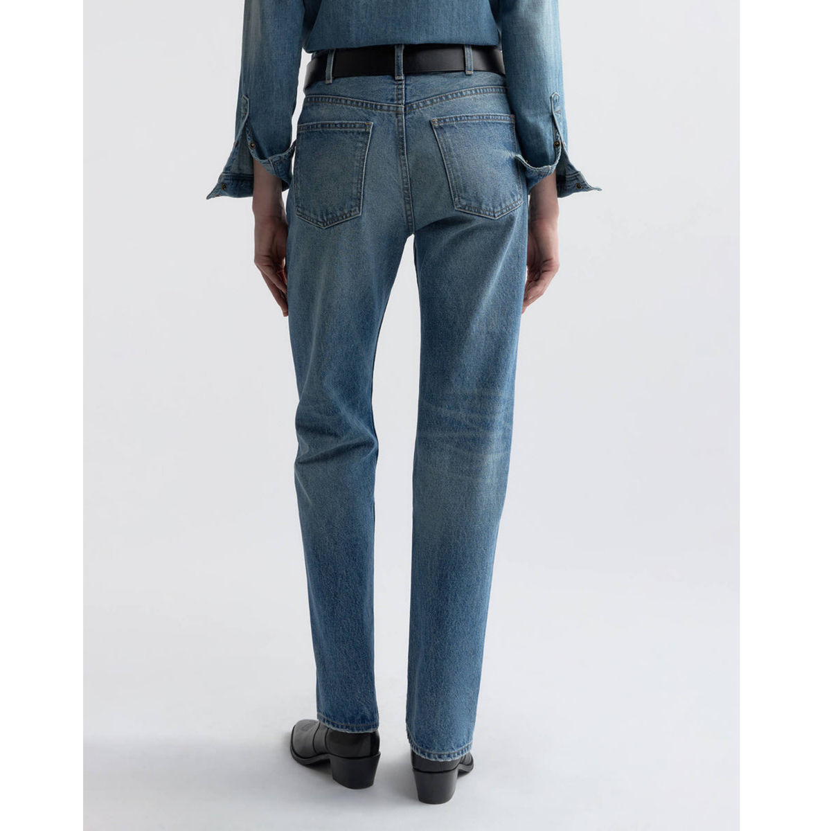 Person wearing blue jeans on a white background