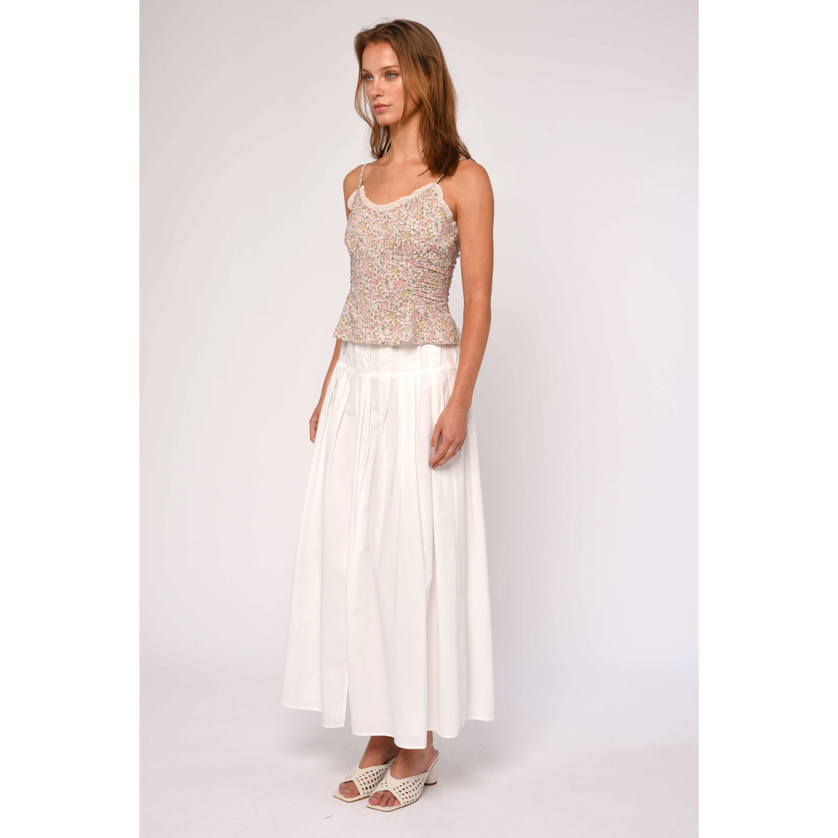 Woman wearing a sleeveless top and white skirt on a plain background