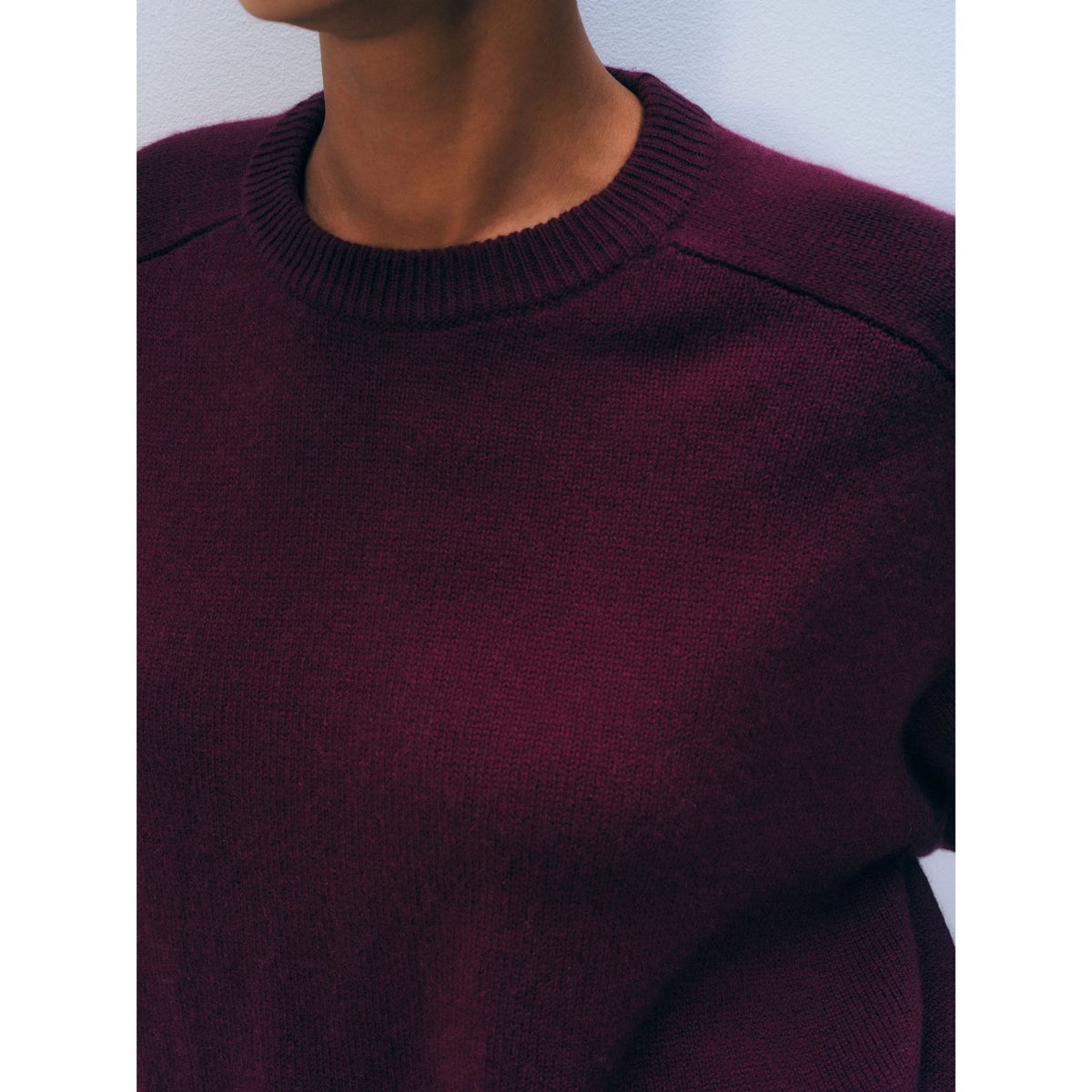 Close-up shot showing the ribbed crew collar, raglan shoulder seam detail, and rich knit texture of the dark Sangria burgundy cashmere sweater.