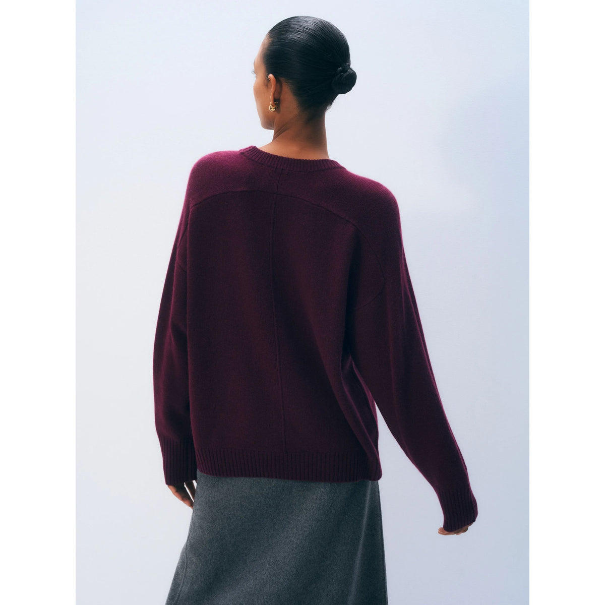 Back view of a model wearing the dark Sangria burgundy long-sleeve cashmere crewneck sweater.
