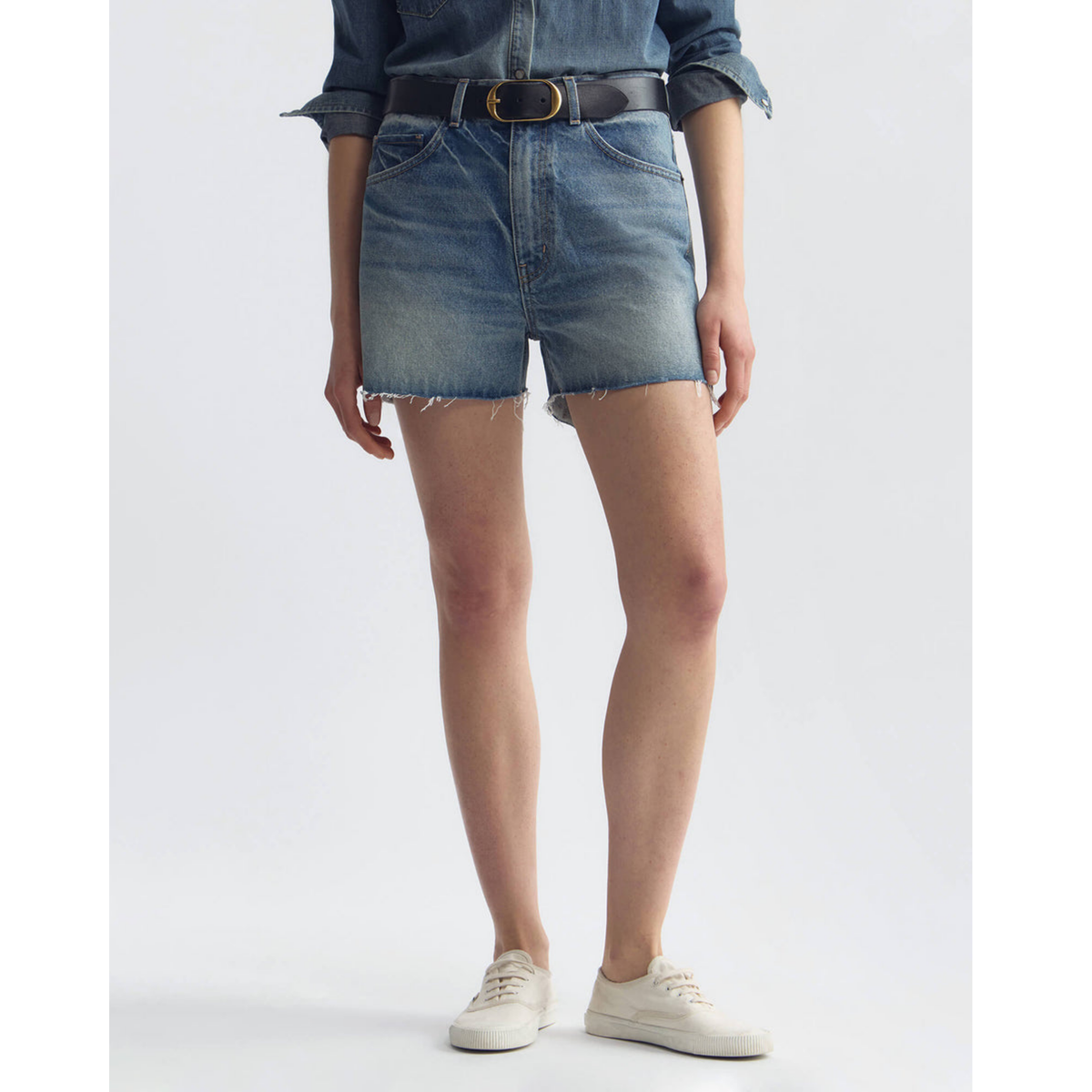 Person wearing blue denim shorts on a white background