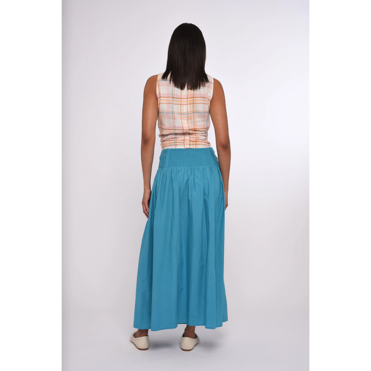 Woman wearing a plaid top and blue skirt on a white background