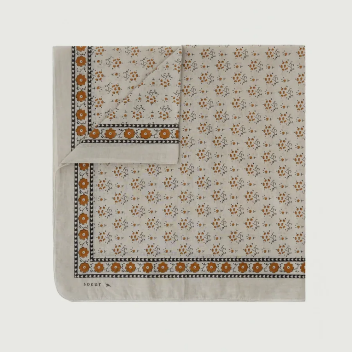 A square scarf with a cream base, featuring a repeating brown and orange floral pattern and a decorative border, laid flat on a light gray background.