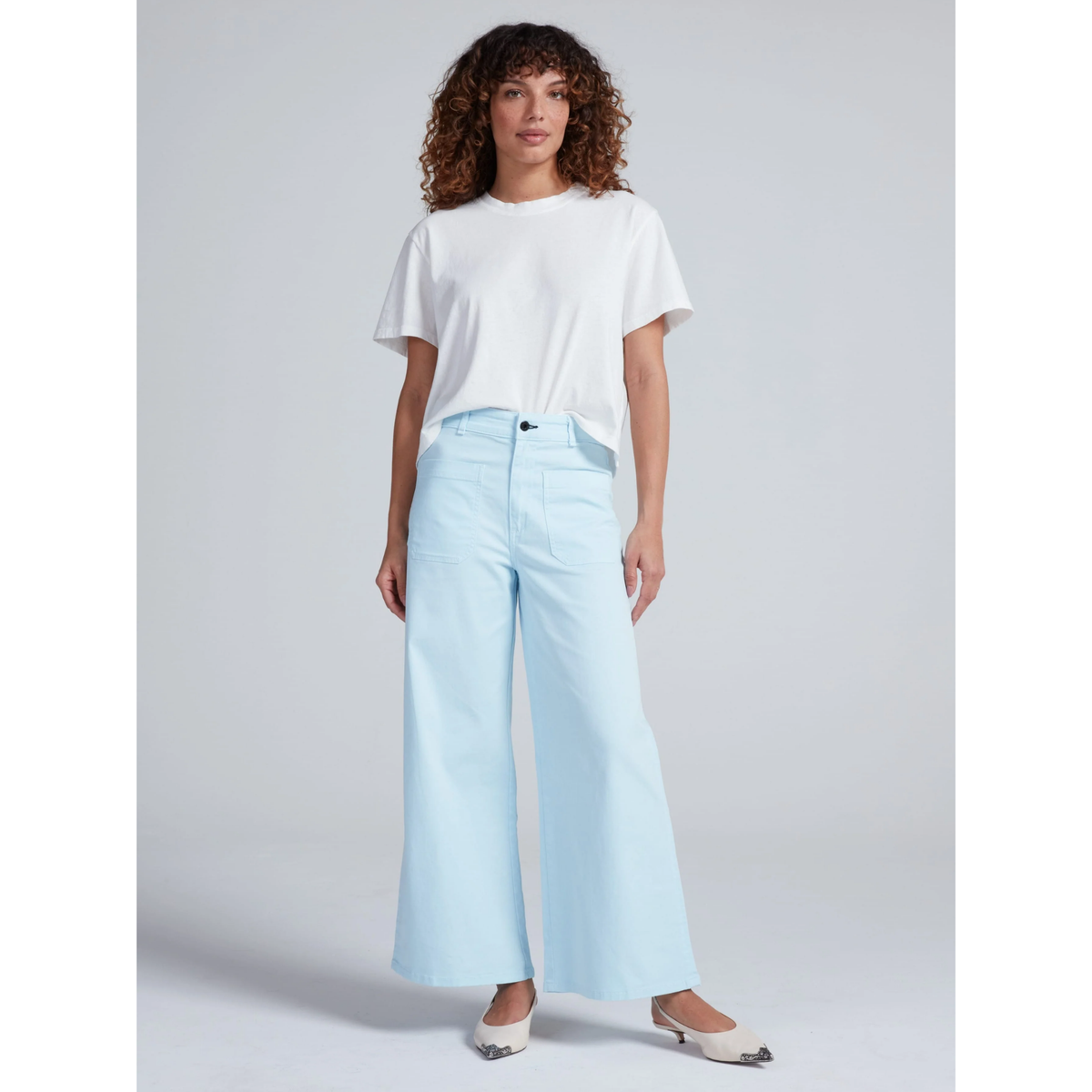 Woman wearing a white t-shirt and light blue jeans on a gray background