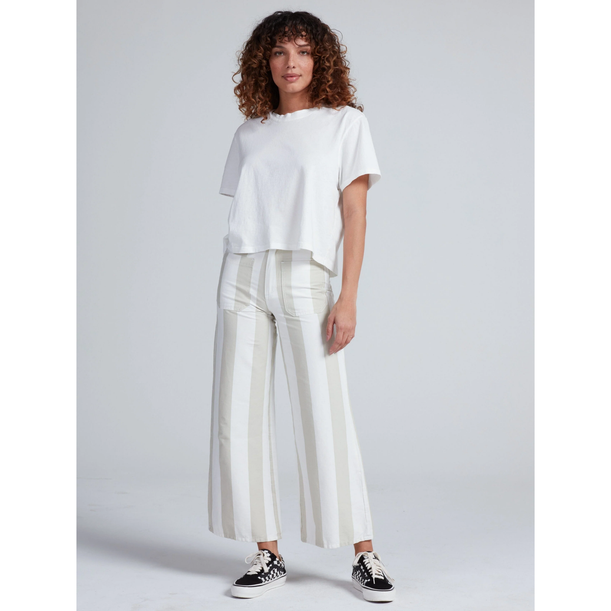Woman wearing a white t-shirt and striped pants on a plain background