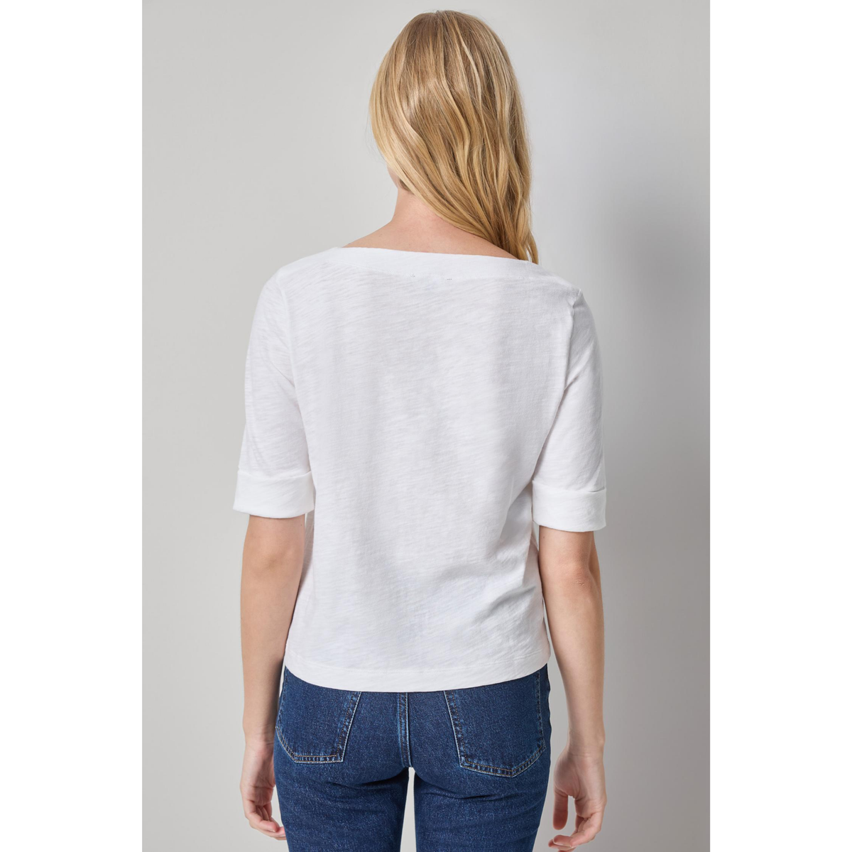 Woman wearing a white blouse and blue jeans on a gray background