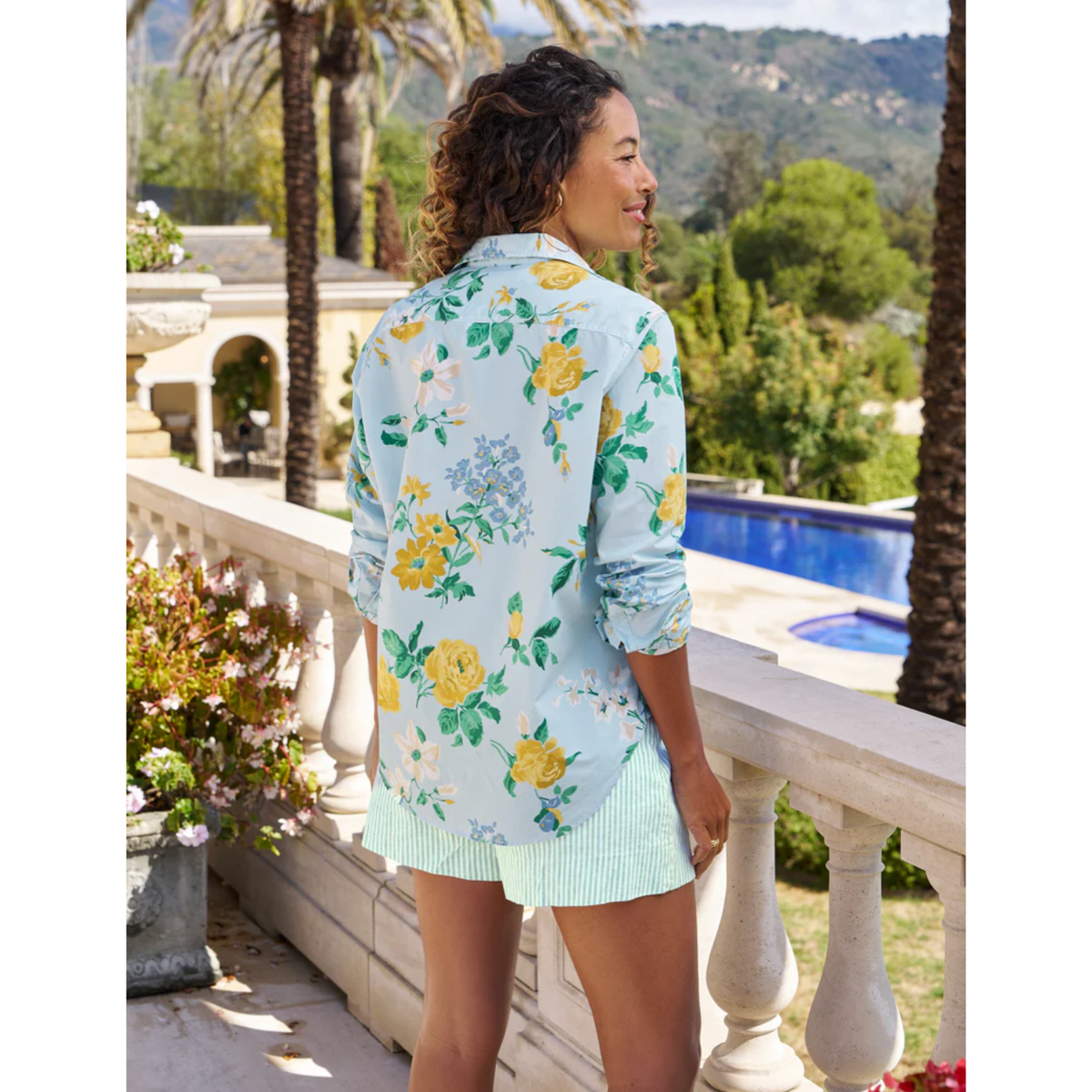 Woman wearing a floral dress with a pool and garden in the background