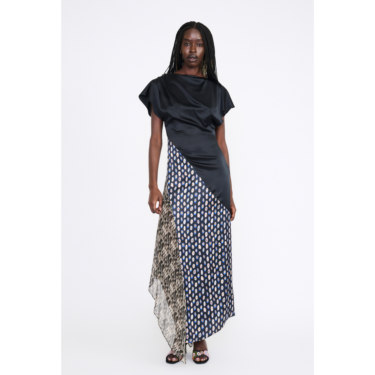 A model wearing a draped, asymmetrical maxi dress with a black satin top section, a navy and white patterned skirt, and a leopard-print side panel, photographed against a plain white studio background.