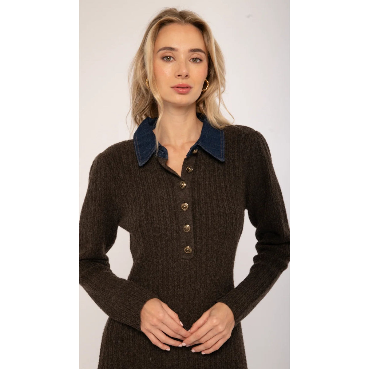 A woman modeling a dark brown ribbed knit long-sleeve polo dress with a contrasting dark blue corduroy collar and brown buttons.