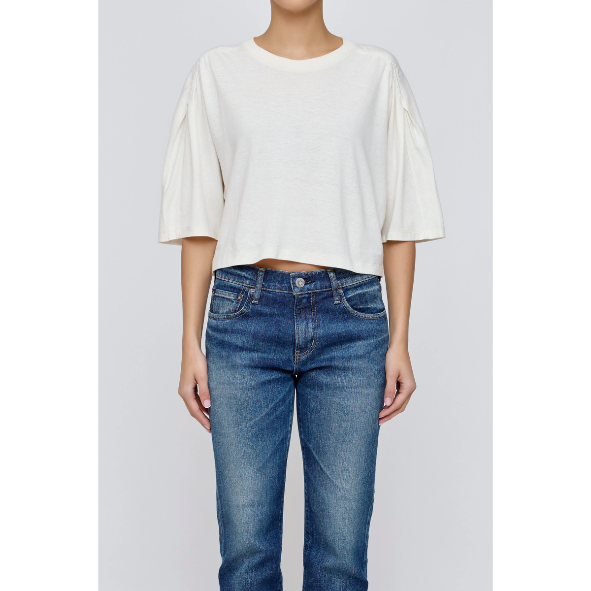 Person wearing a white top and blue jeans on a plain background