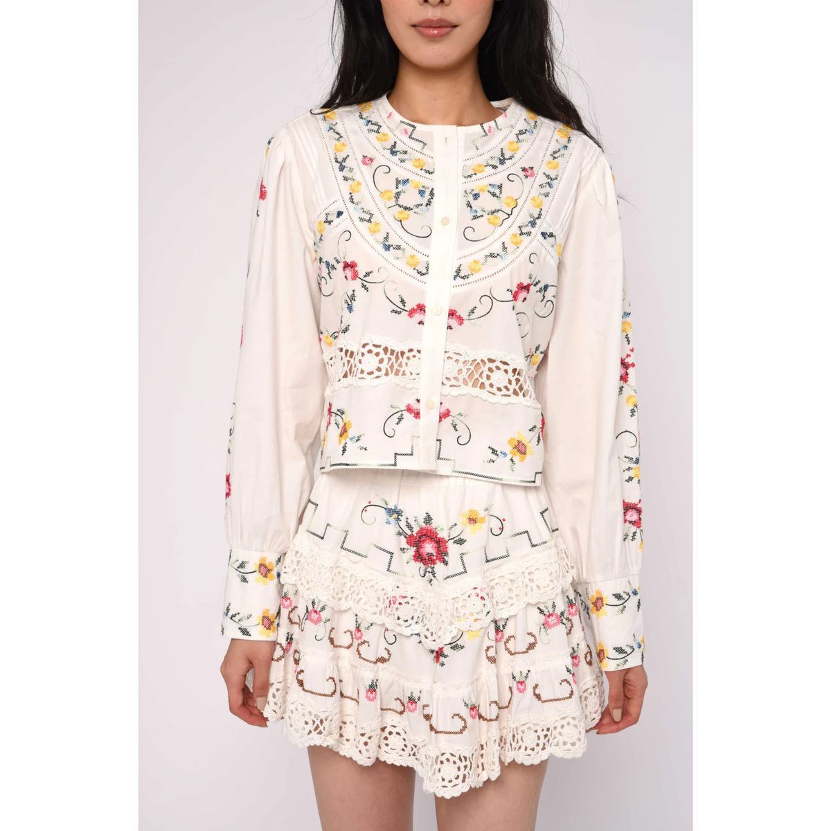 Woman wearing a floral embroidered outfit on a plain background