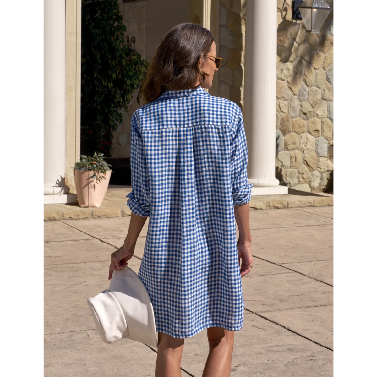 Woman wearing a blue and white checkered dress walking outdoors.