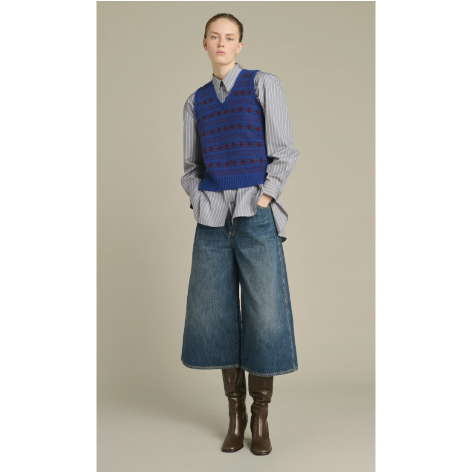 A sleeveless knit sweater vest in deep blue with a red geometric pattern, displayed flat against a light gray background.