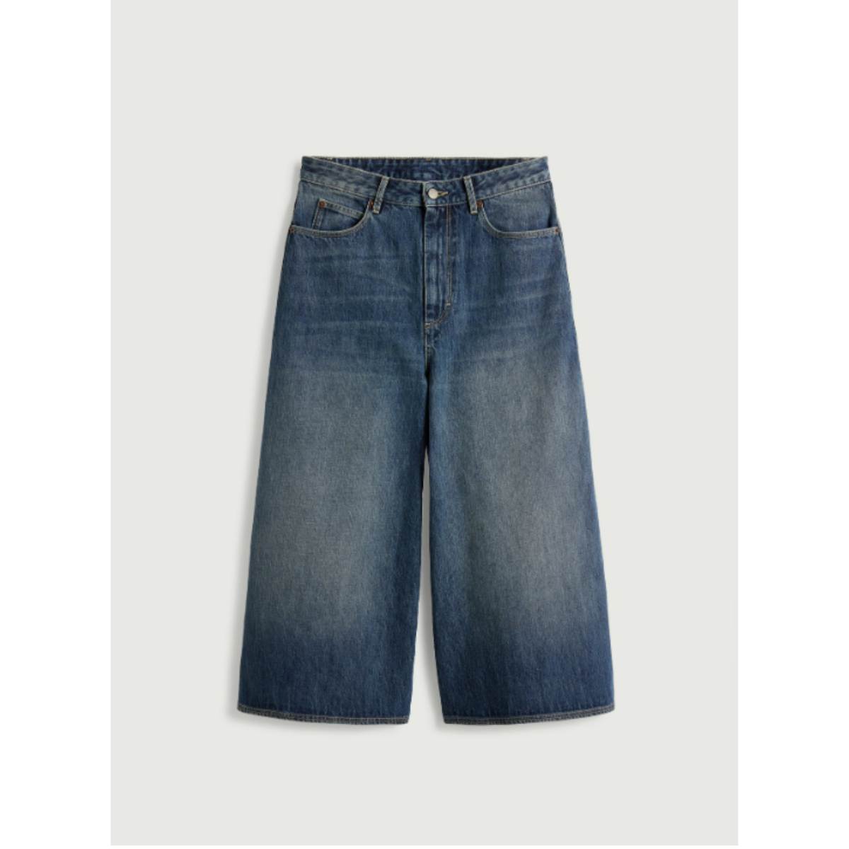 A pair of wide-leg cropped denim shorts in a medium blue wash with a faded, lighter blue gradient towards the lower legs, shown flat on a light gray background.