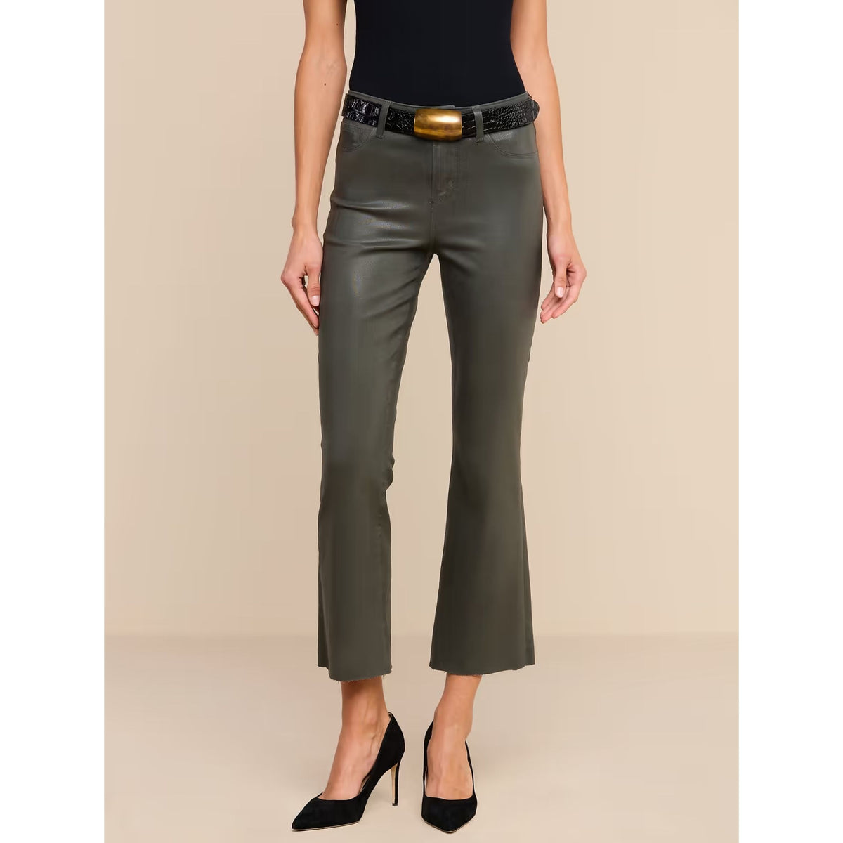 A model wearing a pair of dark olive green cropped flare pants with a black belt featuring a gold buckle, styled with a black top and black high heels against a beige studio background.