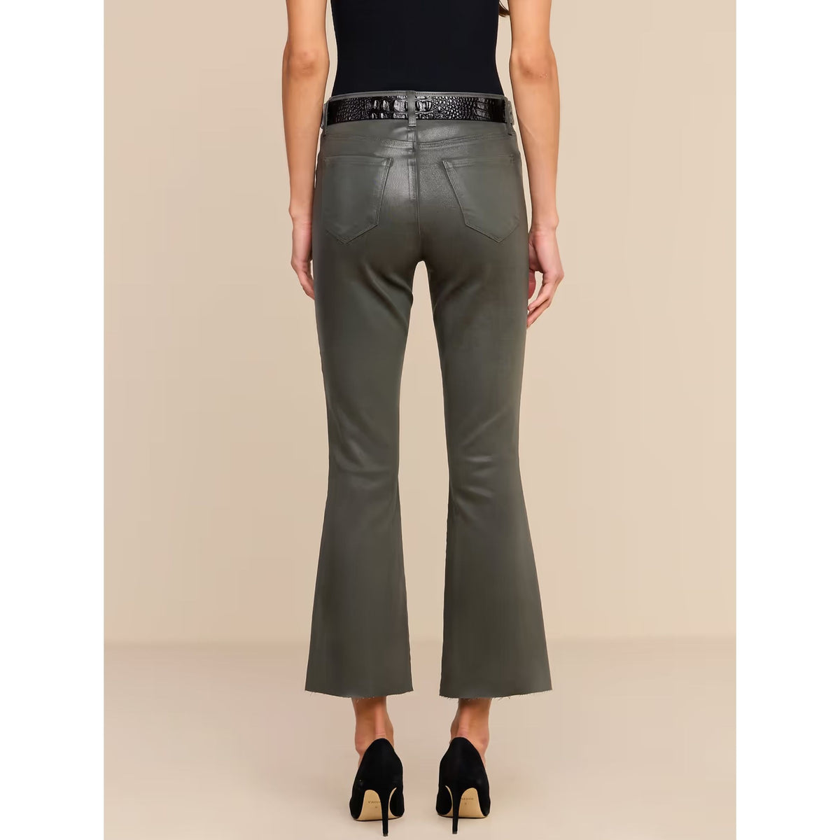A model shown from the back wearing dark olive green faux-leather flare pants with a black belt, a black top, and black high heels against a beige studio background.