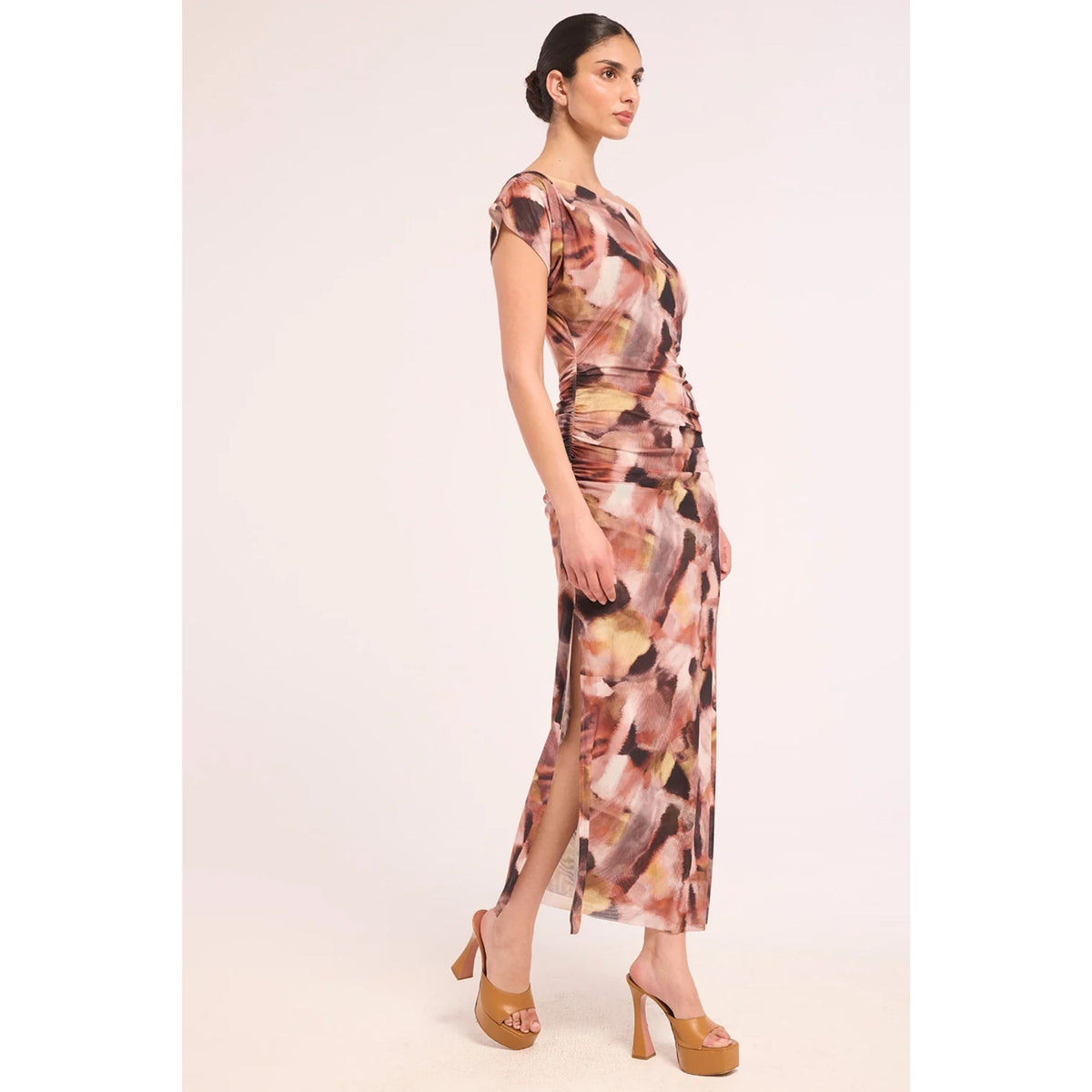 A woman modeling a sleeveless, wrap-style maxi dress with a brown, beige, and black abstract floral print, paired with tan platform sandals, set against a plain light background.