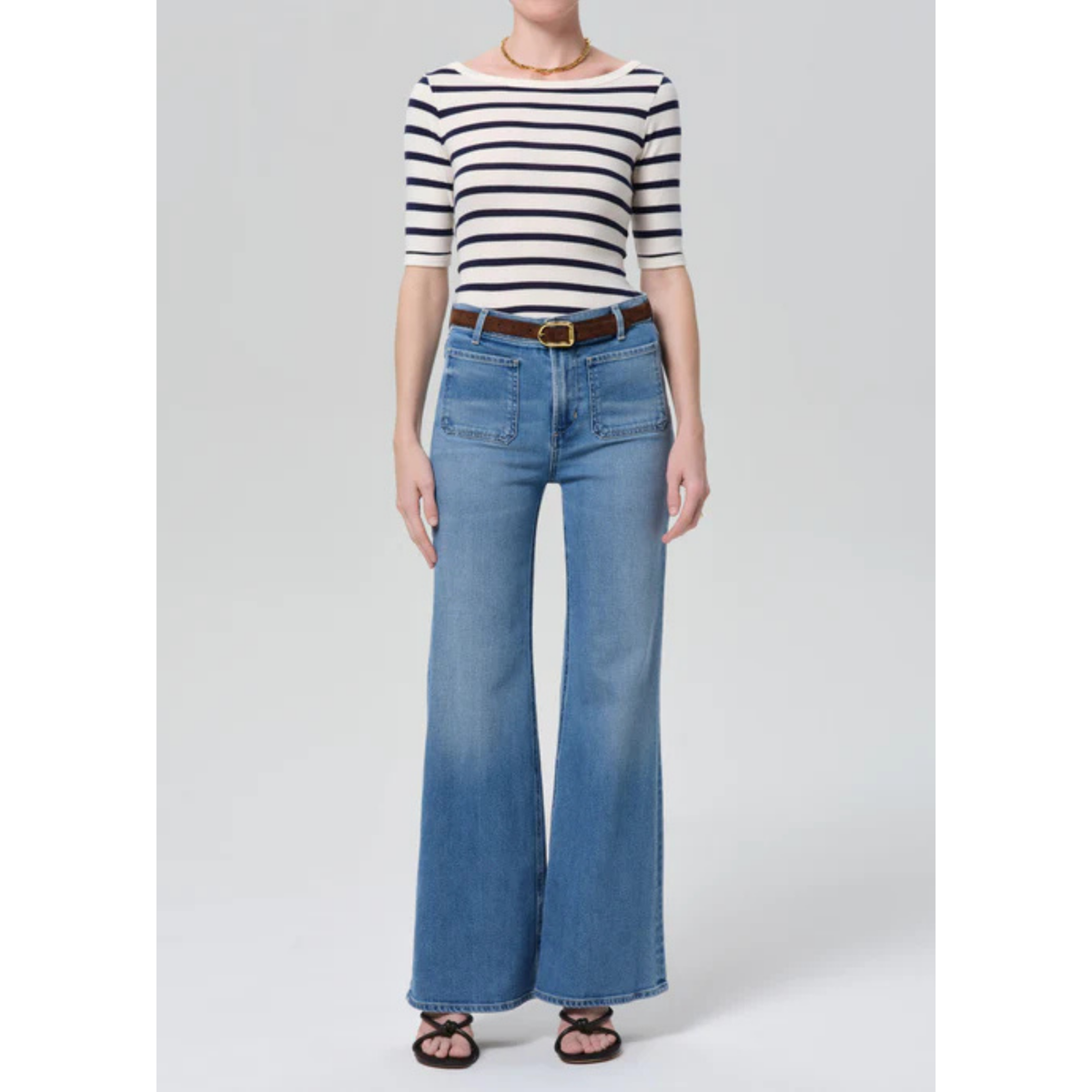 Person wearing a striped shirt and blue jeans on a plain background