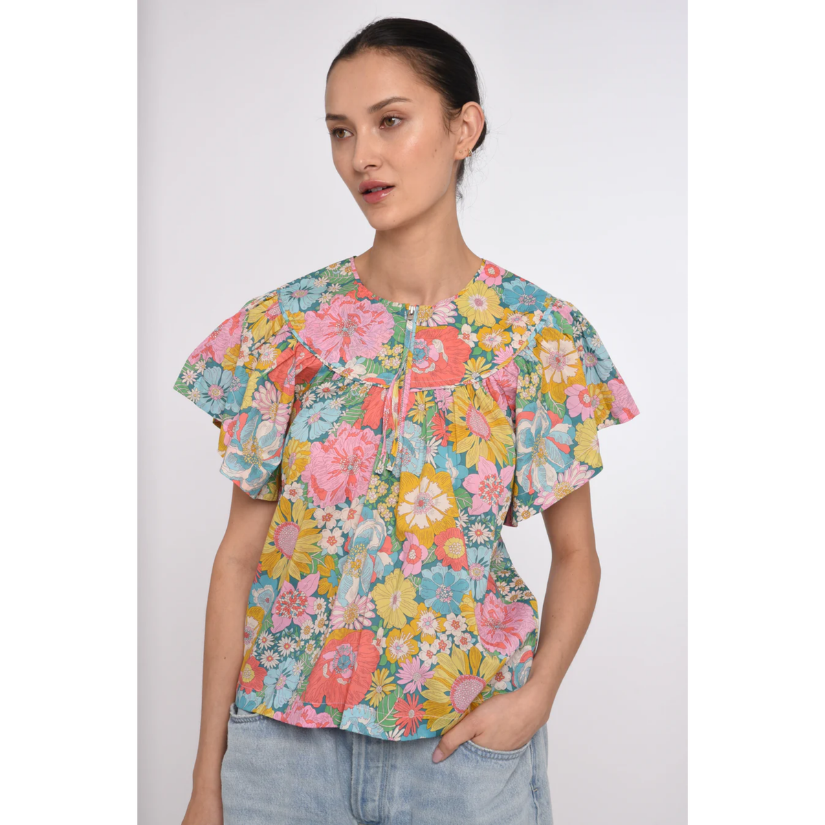 Woman wearing a colorful floral blouse against a white background