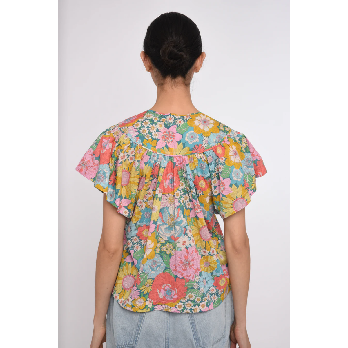 Person wearing a colorful floral blouse with a plain background