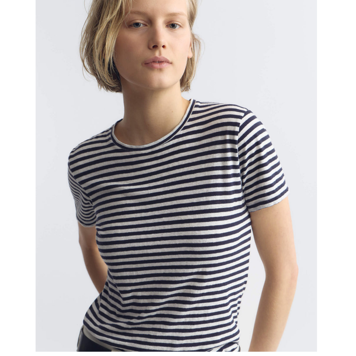 Person wearing navy and white striped shirt on a plain background