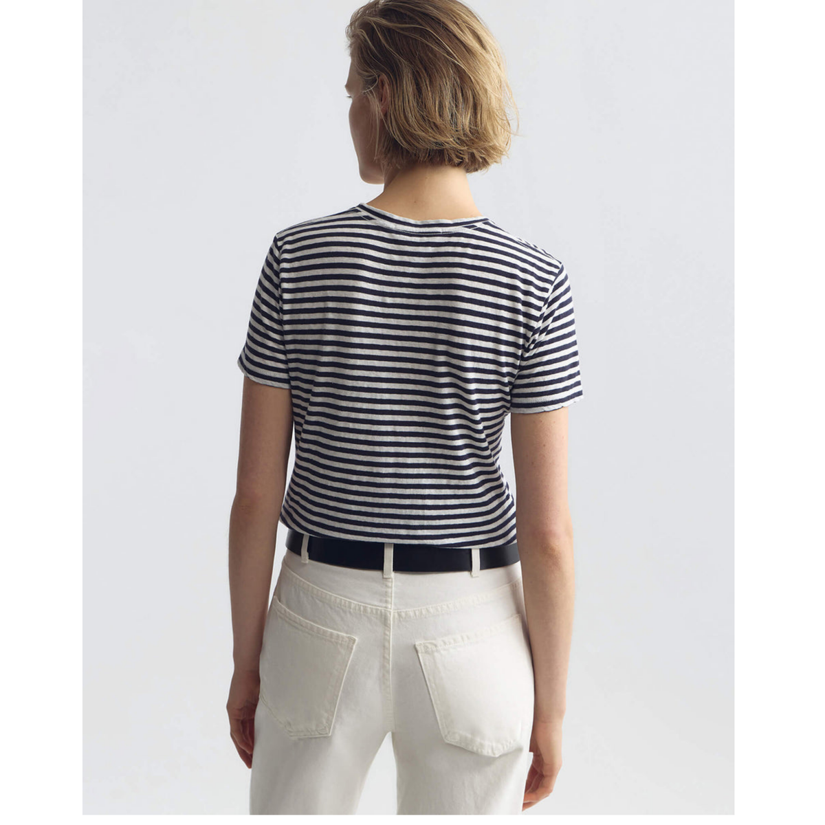 Person wearing a navy and white striped shirt with white pants on a light gray background
