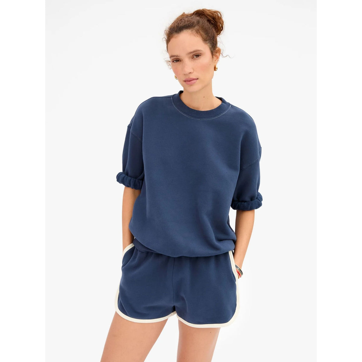Front view of a model wearing the "Le Jogging Short" in solid navy with cream piping trim, paired with a matching short-sleeve navy oversized sweatshirt.