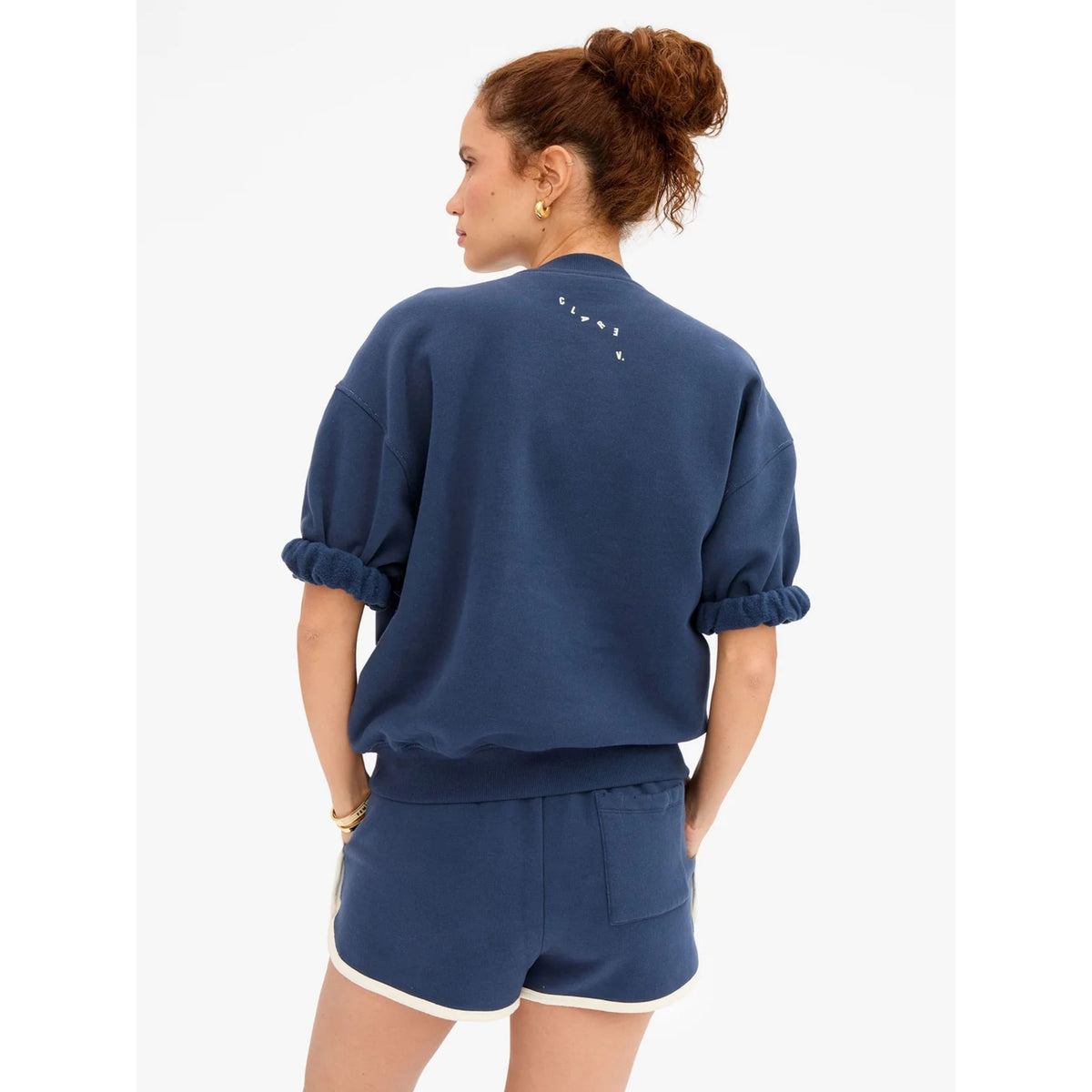 Back view of a model wearing the navy sweat shorts with cream piping paired with a navy short-sleeve sweatshirt.