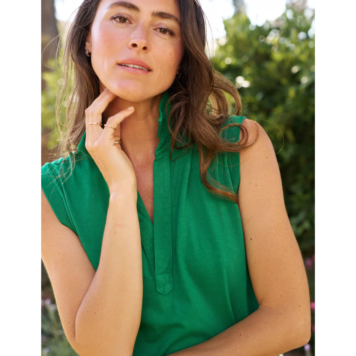Woman wearing a green sleeveless top with a blurred natural background