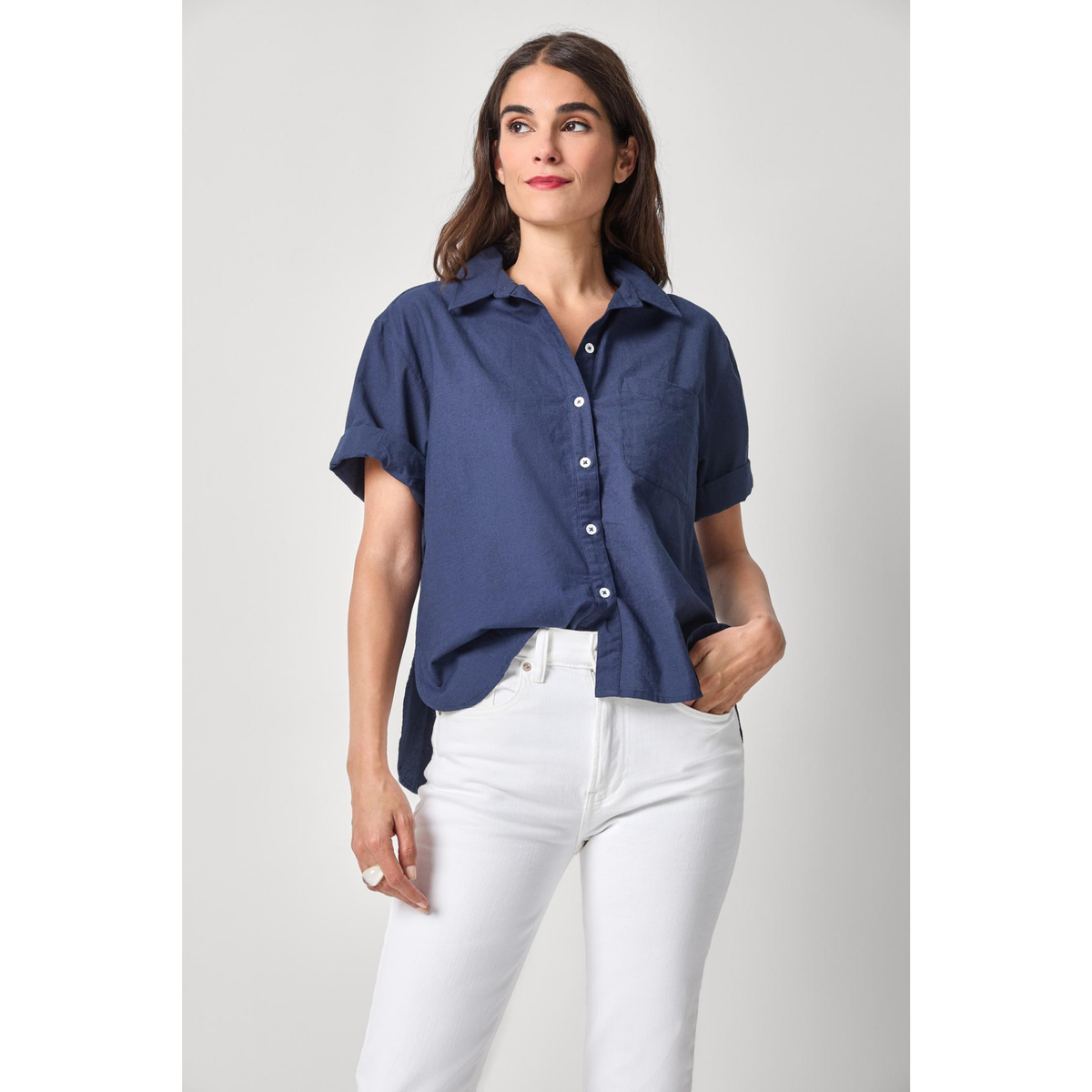 Woman wearing a blue shirt and white pants on a gray background