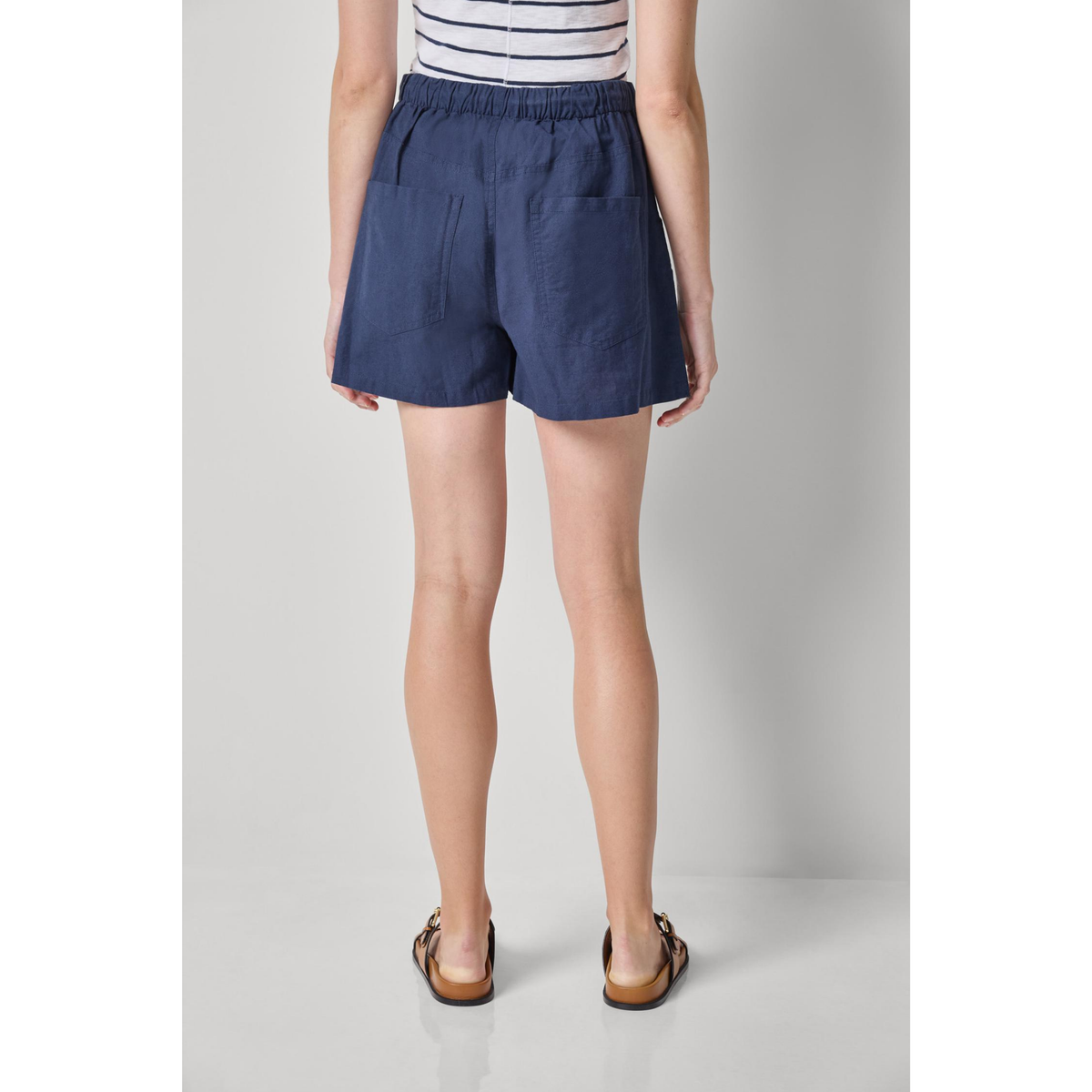 Person wearing navy shorts on a plain background
