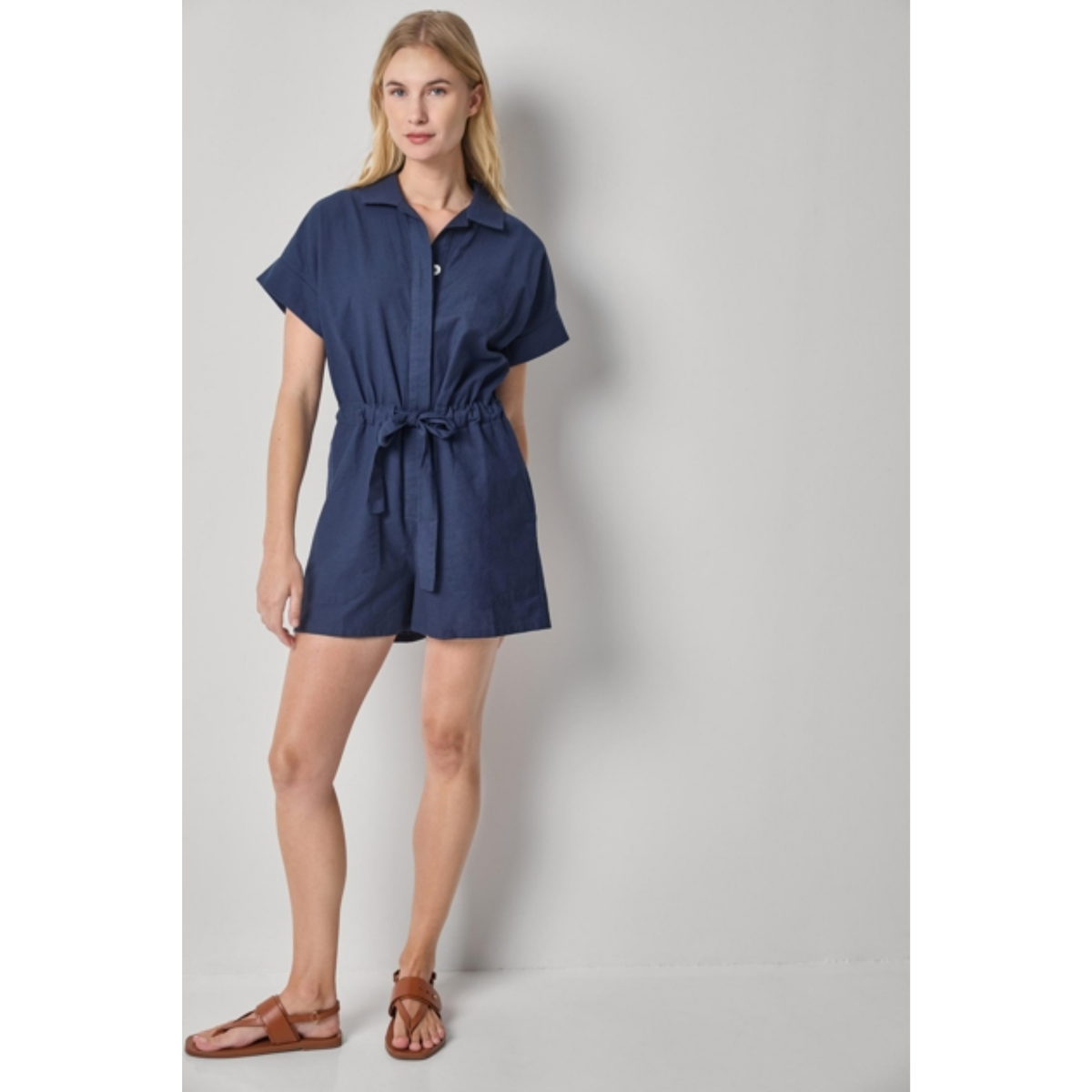 Woman wearing a navy blue romper against a plain background