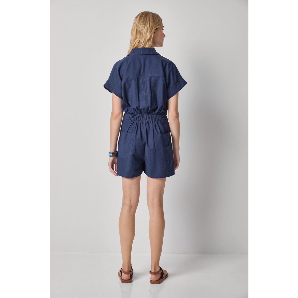 Woman wearing a navy blue romper against a plain background