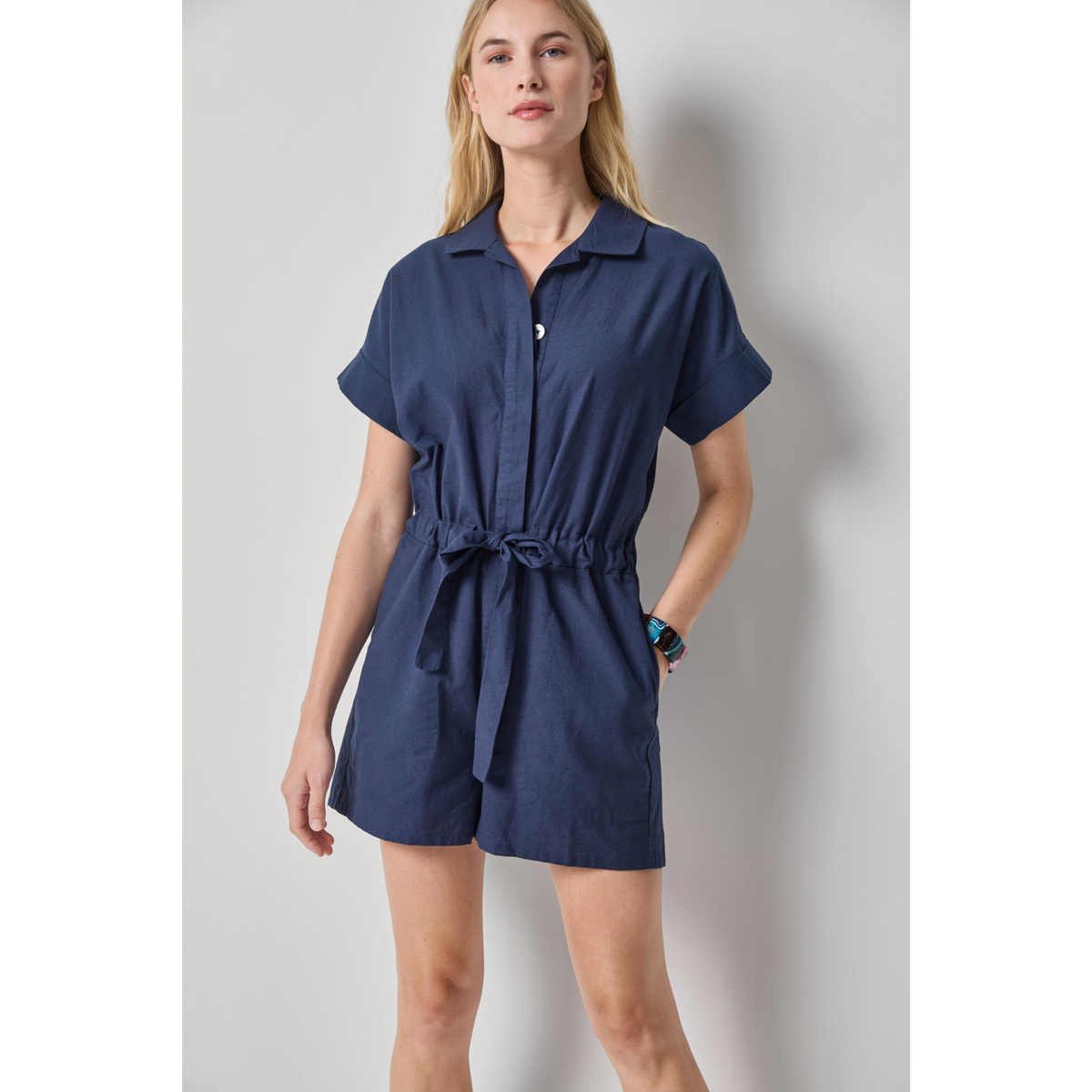 Woman wearing a navy blue romper against a plain background