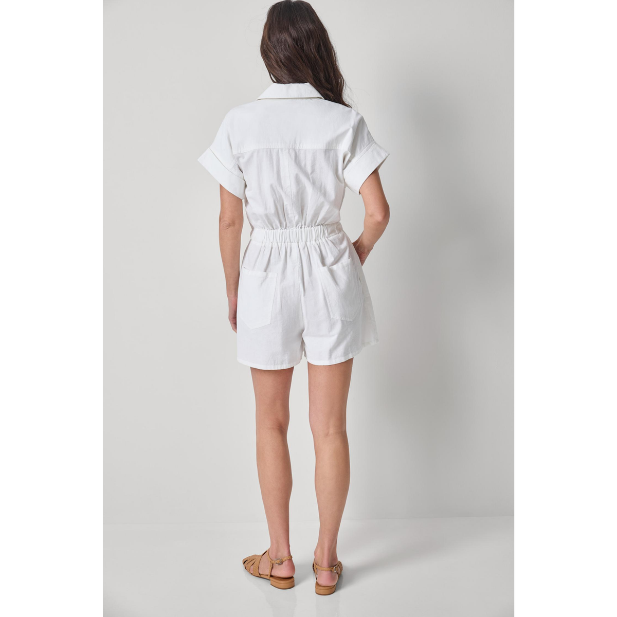 Person wearing a white romper on a plain background