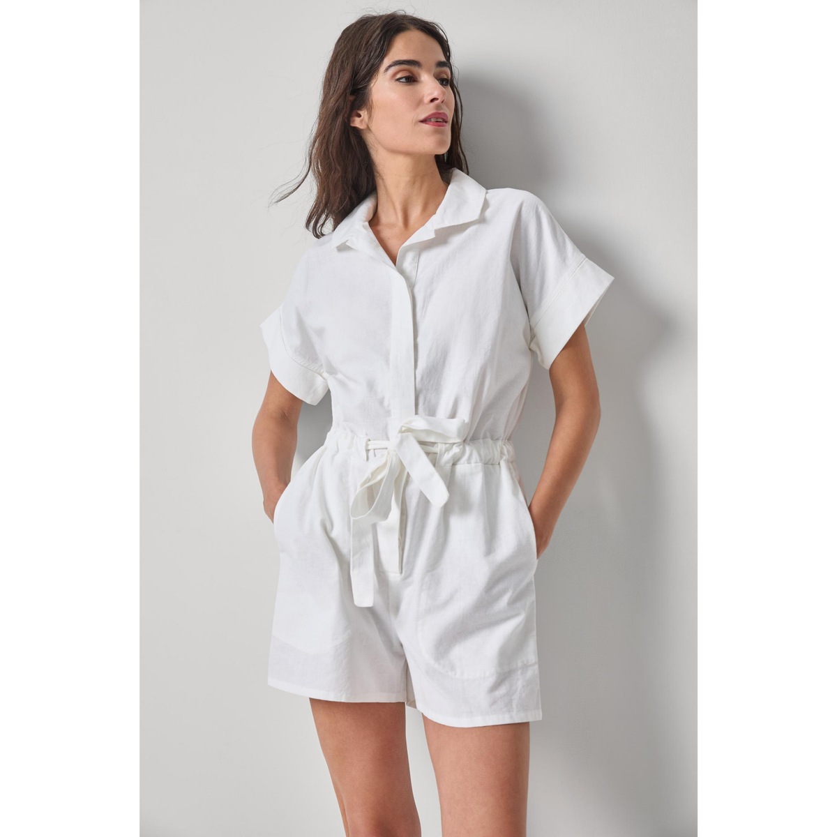 Woman wearing a white romper against a plain background