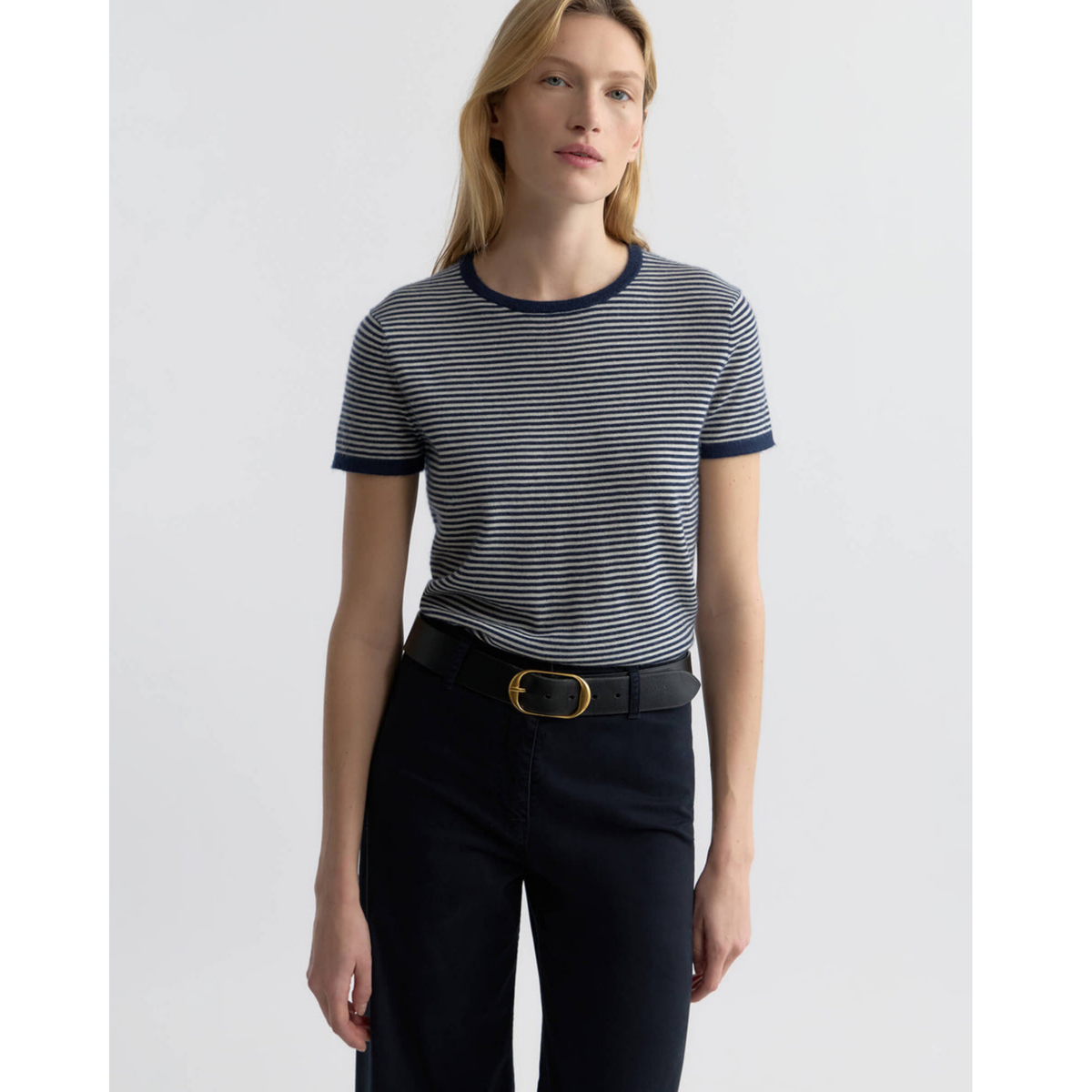 Person wearing a striped shirt and black pants with a belt on a white background