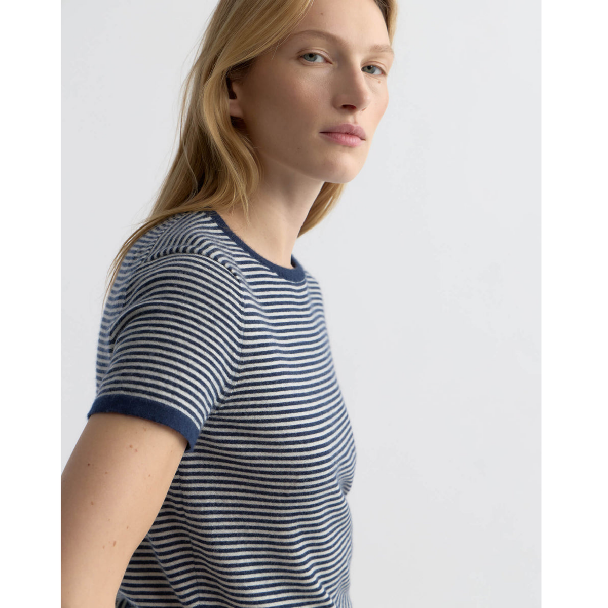 Person wearing a striped shirt and black pants with a belt on a white background