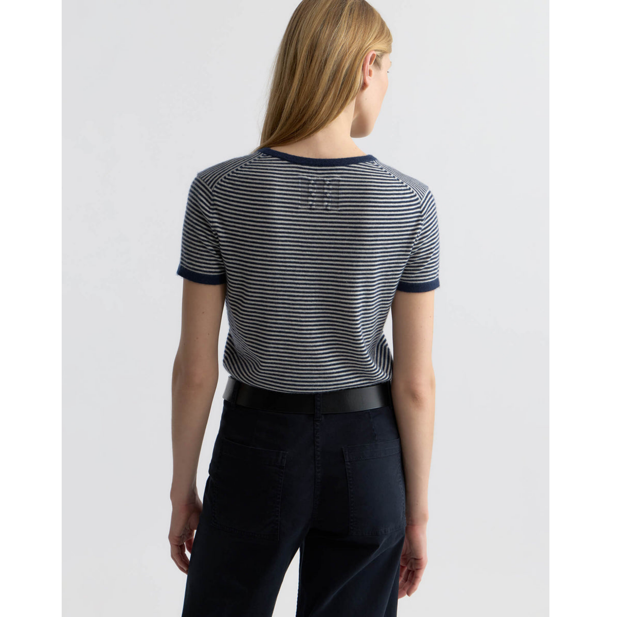 Person wearing a striped shirt and black pants with a belt on a white background