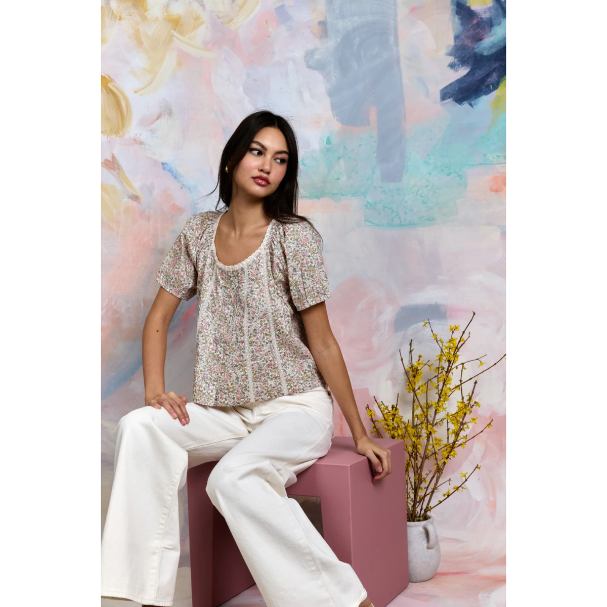 Woman sitting on a pink stool with a colorful abstract background
