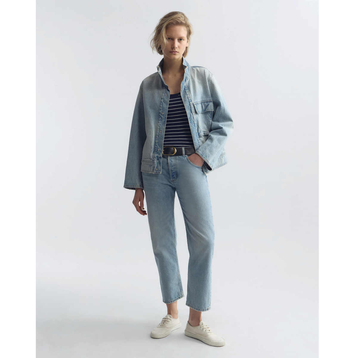 Woman wearing a denim jacket and jeans on a white background