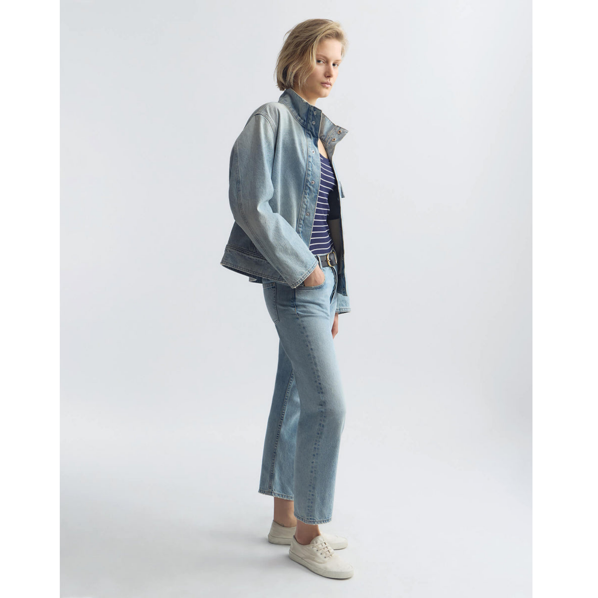 Woman wearing a denim jacket and jeans on a white background