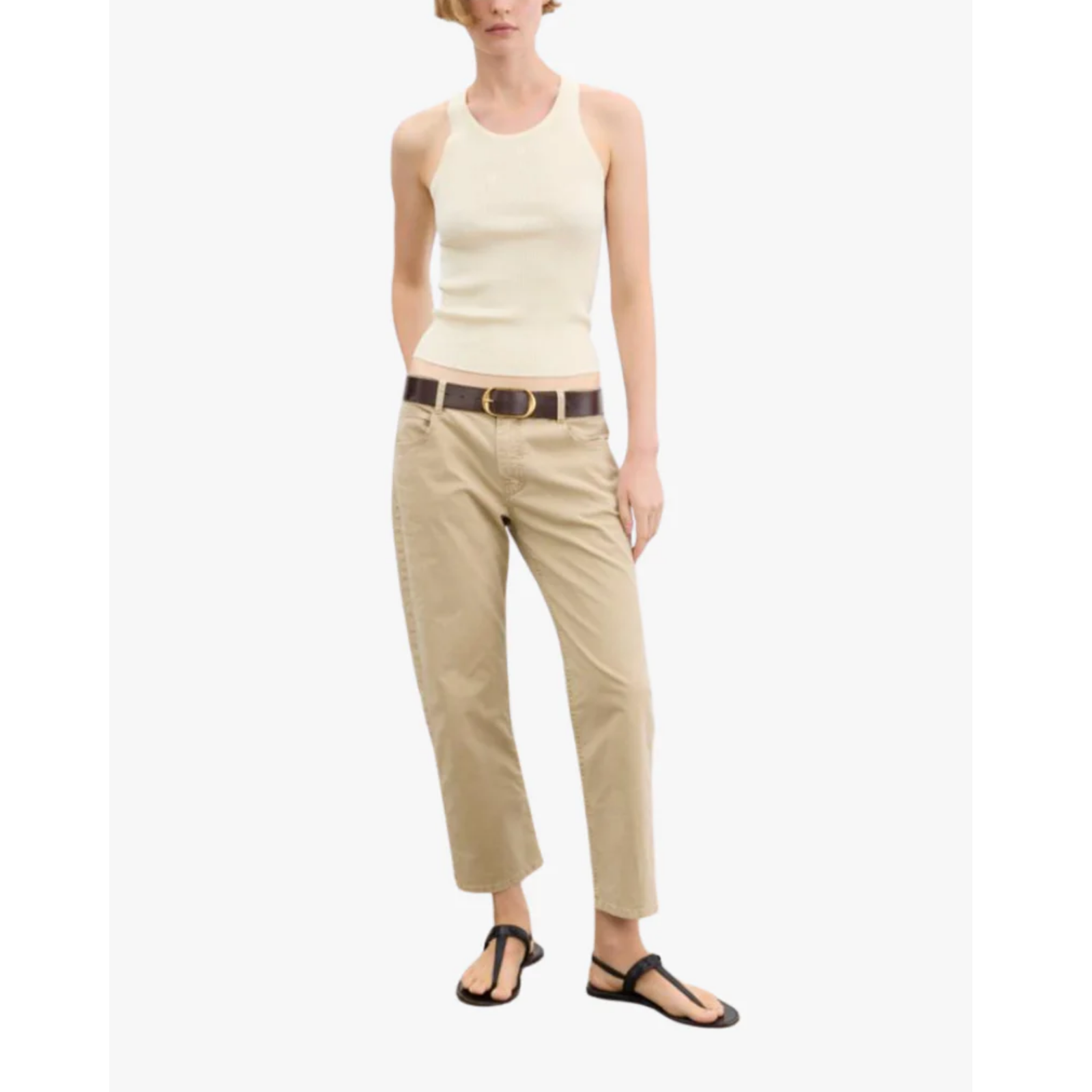 Woman wearing a cream sleeveless top and beige pants on a white background
