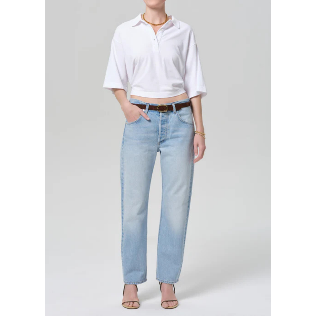 Person wearing a white shirt and light blue jeans on a gray background